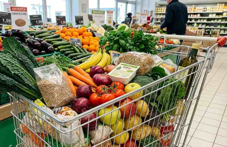 Carrello spesa vegetariana piena di prodotti freschi, verdure, legumi e tofu in offerta al supermercato.