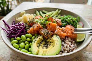 Poke bowl colorata con salmone a cubetti, avocado e verdure fresche servita in un ristorante.